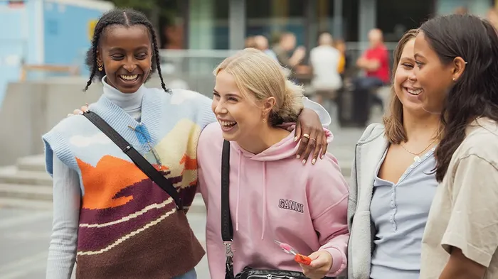 Fire kvinnelige studenter på UiO som smiler, ler og holder armene rundt hverandre