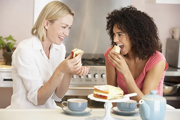Bildet viser to damer som spiser brødskiver