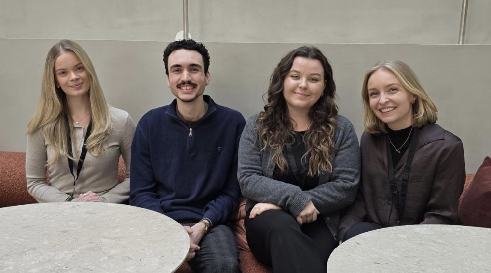 Bildet viser fire studenter smilende i sofa