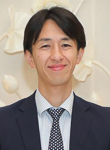 Profilbilde av en smilende Yuichi Mori, kledd i mørk dress mot en lys bakgrunn.