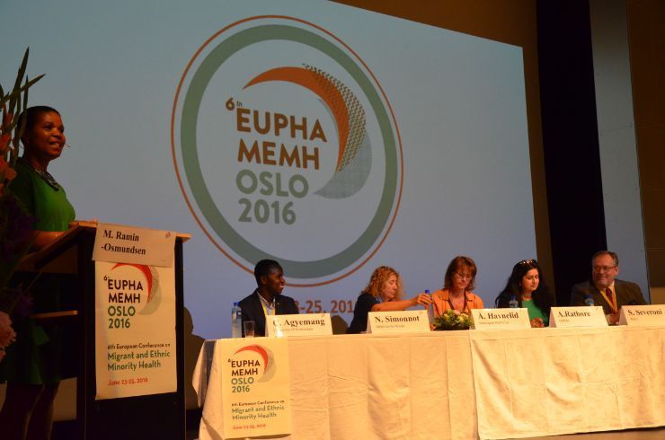 Politician Ramin-Osmundsen speaking from the podium next to the panel participants at the 2016 EUPHA conference.