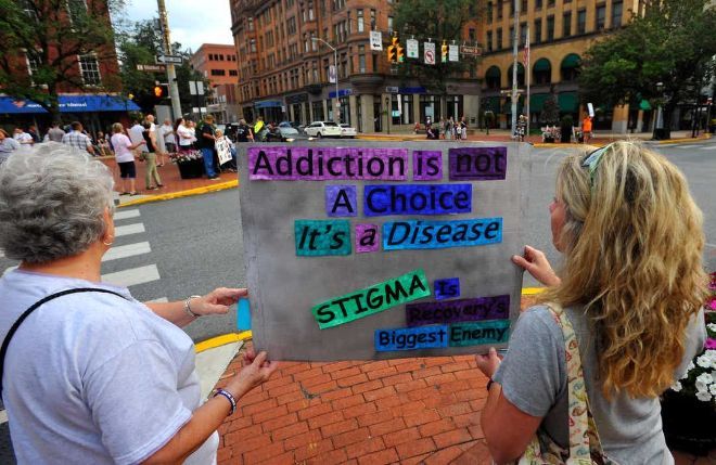 two women in the street holding a poster saying: addiction is not a choice it's a disease, stigma.