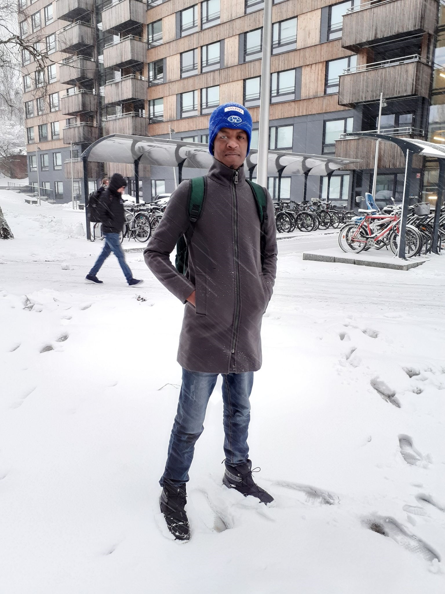 Man in winter clothes in the snow, outside Kringsjå student housing. 