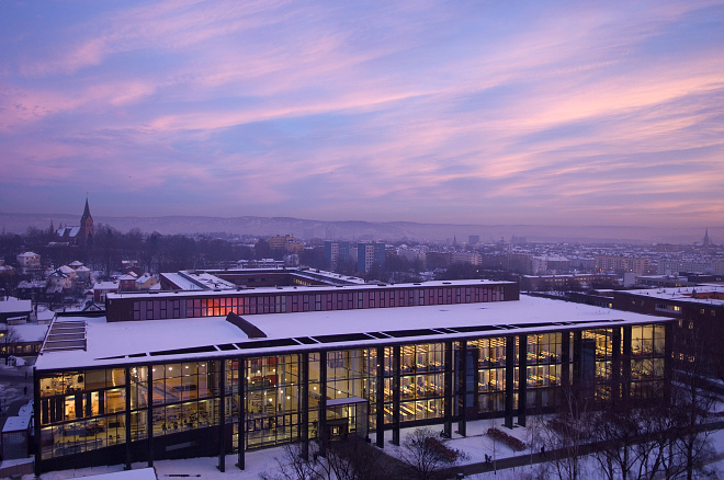 View from above of the University of Oslo campus area, with the new library building, covered in snow and with a beautiful sunset over the city of Oslo.