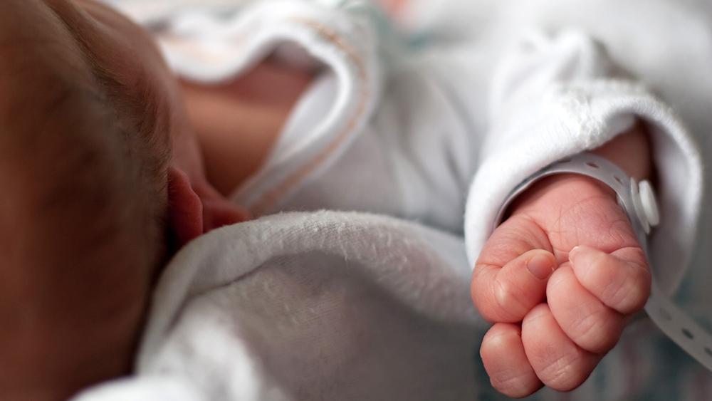 A newborn baby, you cant see his face, his hand is clutched. 