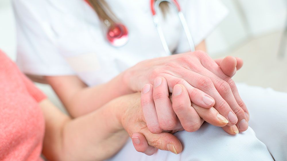 Sykepleier som holder pasients hånd (illustrasjonsfoto)