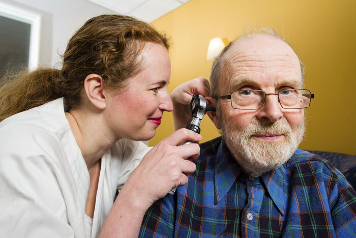 Illustrasjonsfoto AGS, sykepleier ser i øret på eldre mannlig pasient
