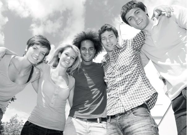 Svart-hvitt-bilde av fem studenter som smiler og støtter seg på hverandre - to unge kvinner og tre unge menn