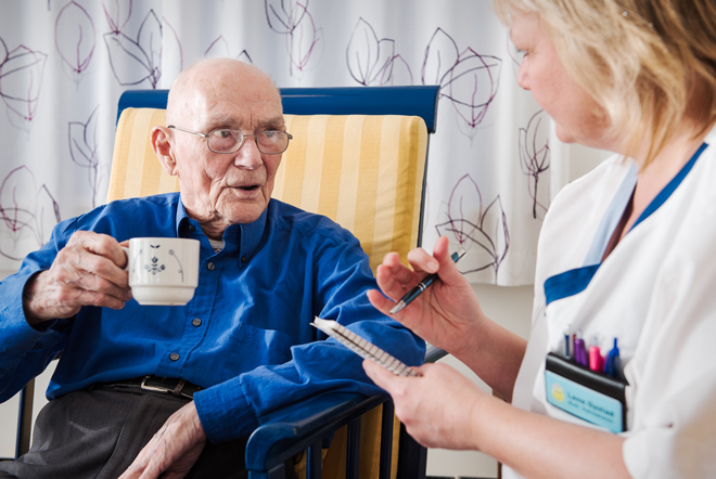 Eldre mann snakker med sykepleier