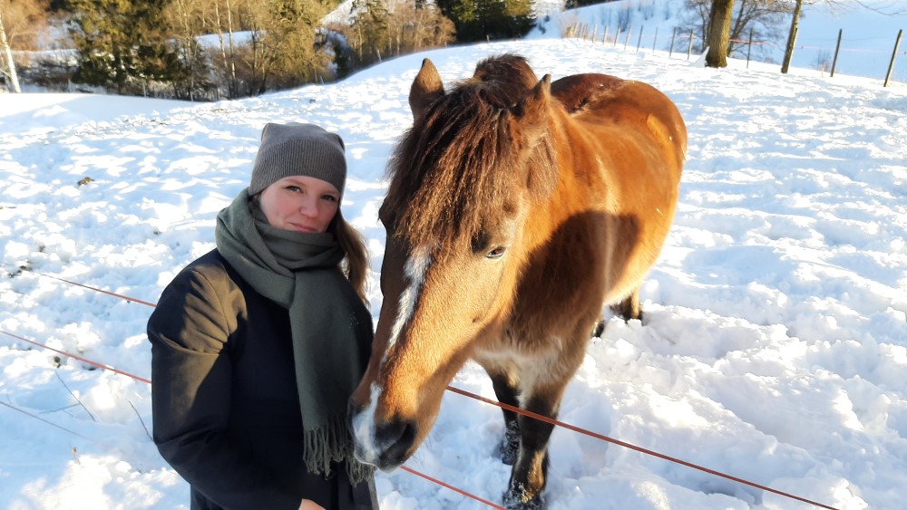Image shows a woman with a horse outdoors in the snow