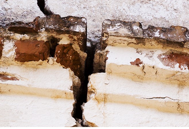 Close up image of a wall breaking down, with a crack running down the middle