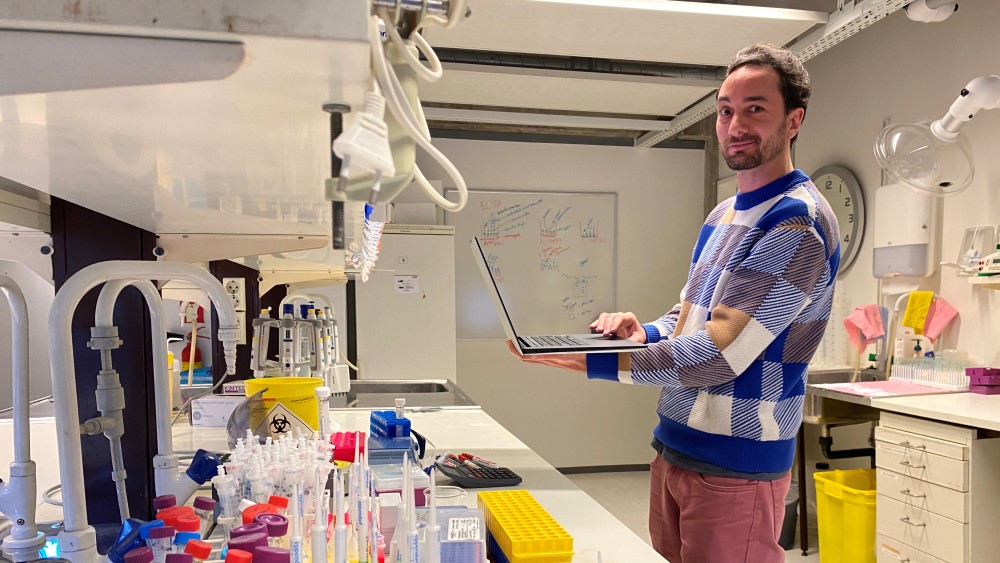 Bildet viser en forsker som står med en laptop på et laboratorium