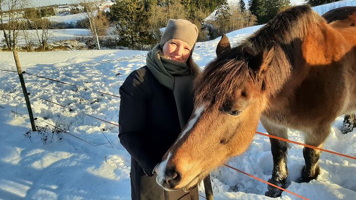 Veterinær Helene Seljenes Dalum står utendørs med en hest.