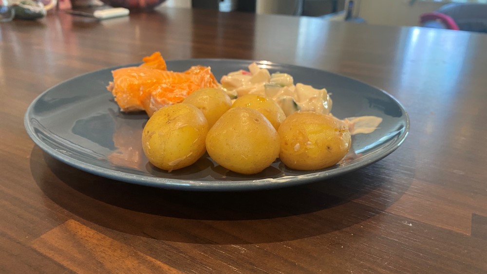 Bildet viser en tallerken med kokte poteter, laks og salat