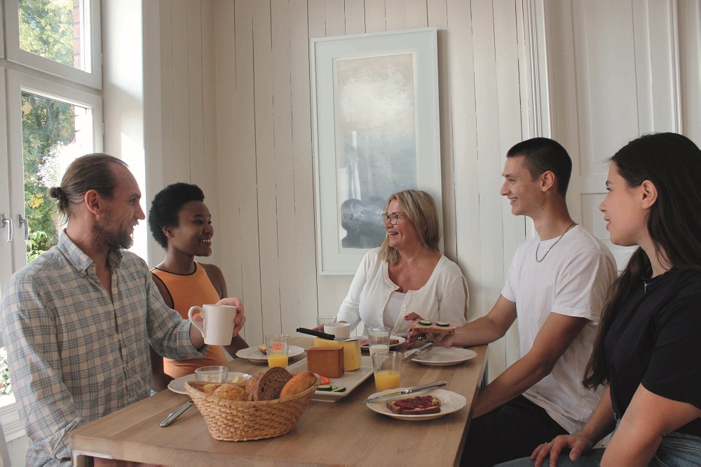 Bildet er av forsiden til invitasjonsbrosjyren i Norkost 4. Overskriften er "Hva spiser vi i Norge?". Det er bilde av en familie som spiser frokost og en snakkeboble med teksten "Vil du være med i undersøkelsen av kostholdet i Norge?"