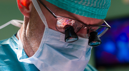 Close up of surgeon during operation. An image of the operation reflected in the surgeons glasses.