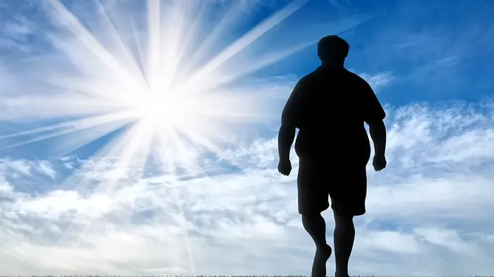 Bilde av en person med fedme hvor man ser personen bakfra. Himmelen og solen er i bakgrunnen.