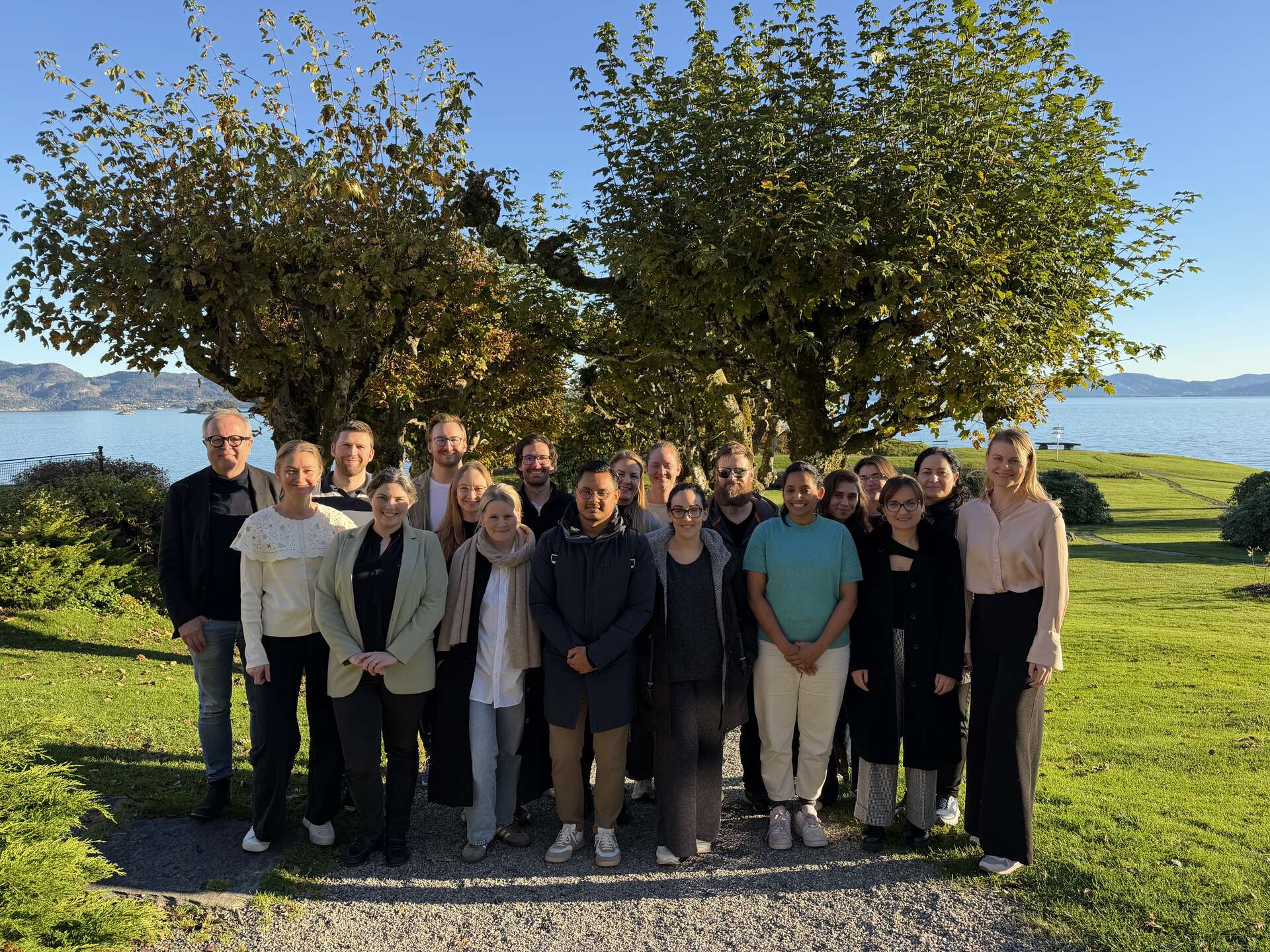 Bildet viser en akademiets medlemmer og møtedeltakere som står samlet en gruppe i solrike naturomgivelser på Solstrand Hotel & Bad.