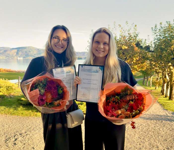 Bildet viser prisvinnerne stående i solrike naturomgivelser, vinnerne har hver sin blomsterbukett og pris i hendene.