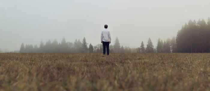 Menneske med ryggen til i naturen, naturlig landskap, tåke.