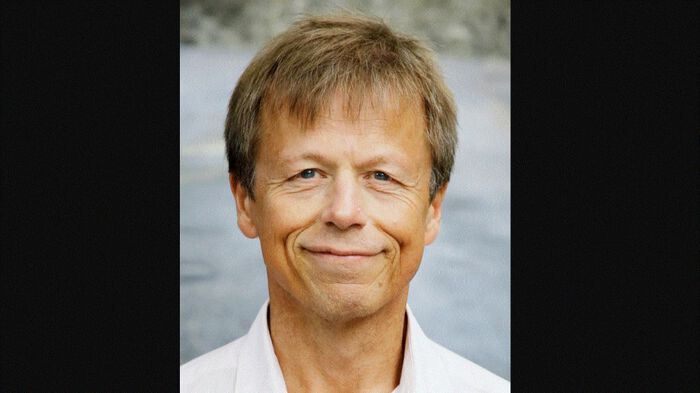 smilende mann med sjø i bakgrunnen.