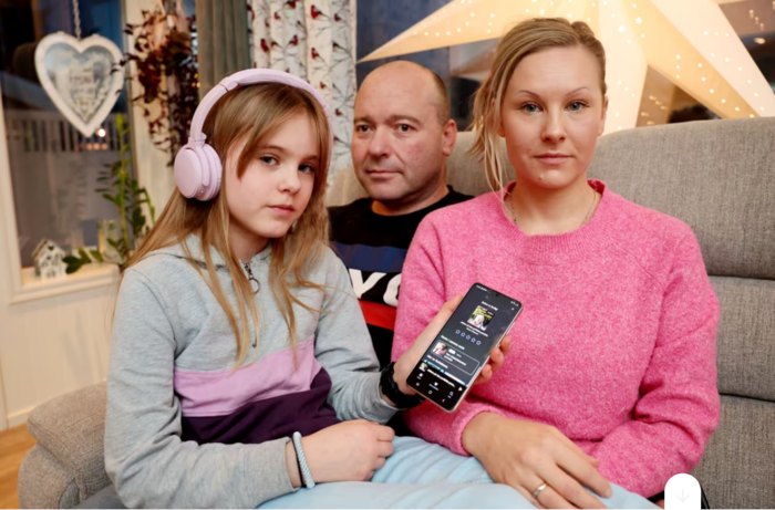 Barn, far og mor i en sofa med hodetelefon og mobil. Foto  