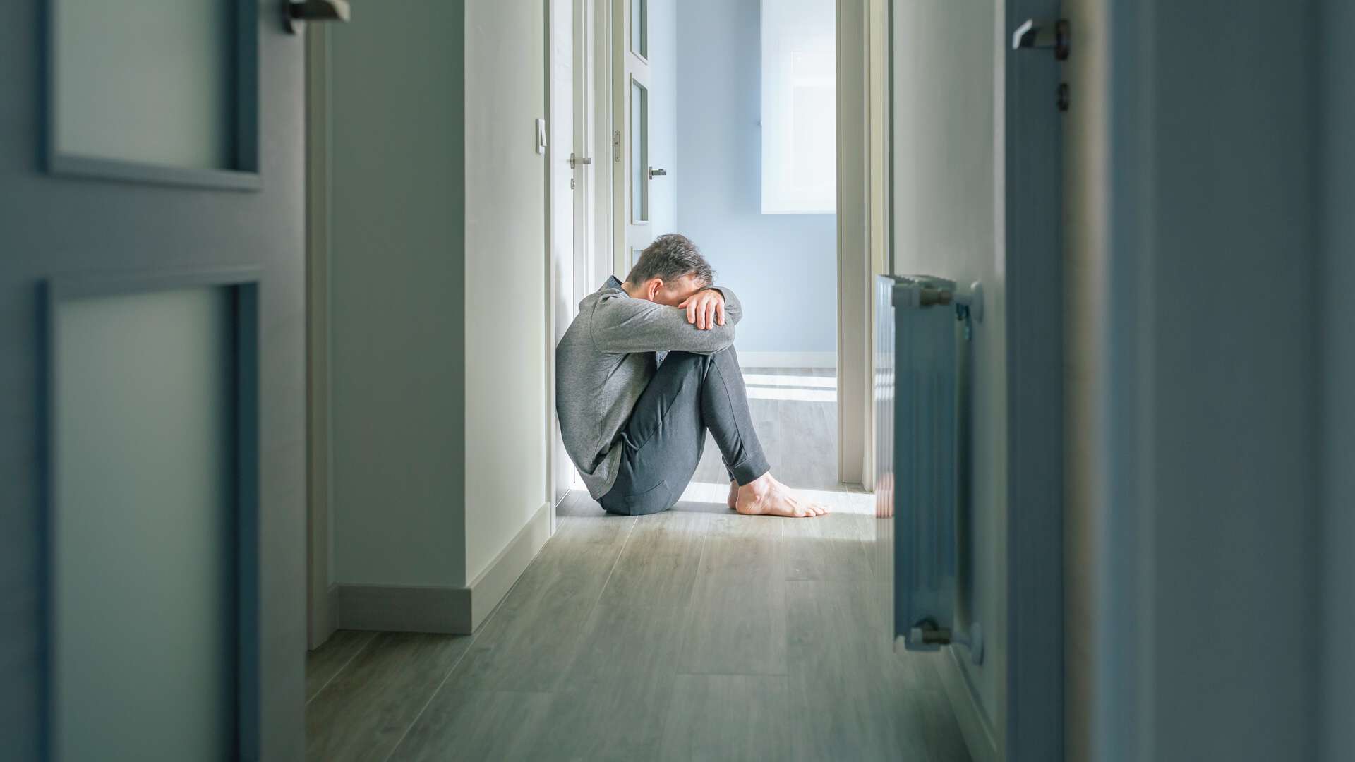 Bildet viser en mann som er svært lei seg og sitter på gulvet. 