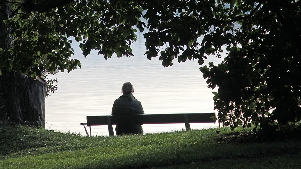 ensom kvinne sitter alene på en benk