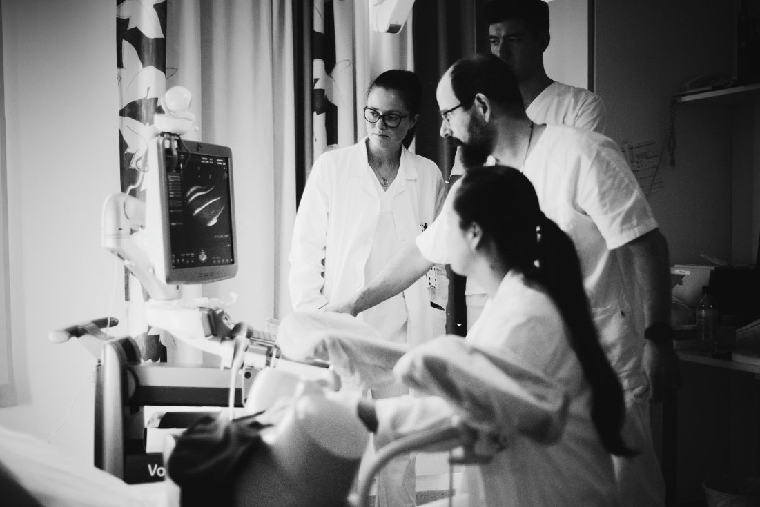 Teacher explains to medical students the image seen on the screen of an ultrasound scanner.