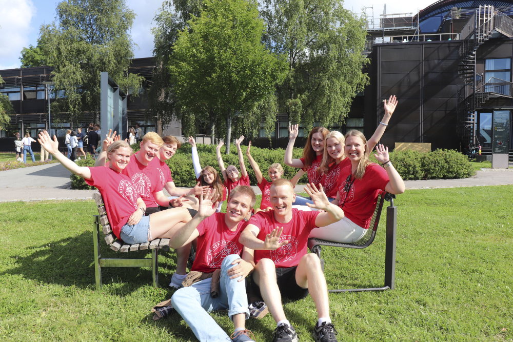 Glade studentfaddere sitter samlet på gresset.