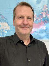 Portrait picture of a man standing in fron of the World map.