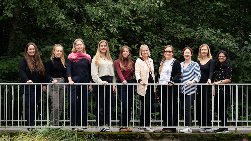 Ten members of the Haapaniemi group standing on a bridge with trees in the background