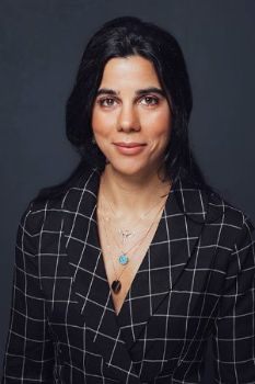 An image of Dr. Irep Gözen wearing a black blazer with white stripes and a blue necklace