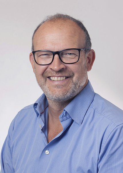 Profile of Poul Nissen smiling at the camera wearing glasses and a blue shirt