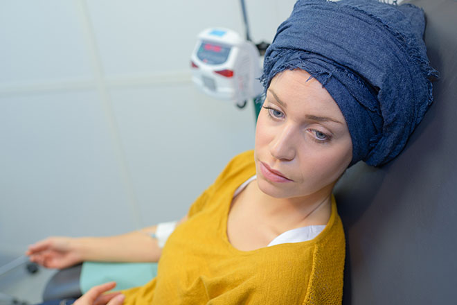 Kvinne som mottar behandling. Blått skjerf på hodet skjuler hårmangel.