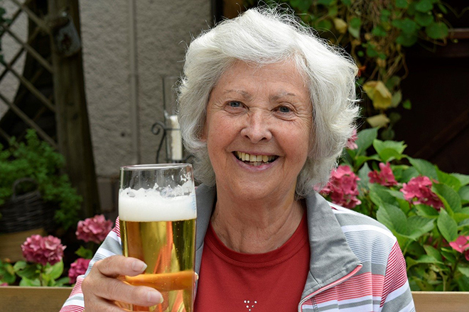 Fornøyd gråhåret dame med et glass øl.