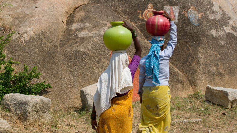 To kvinner som bærer vann på hodet.