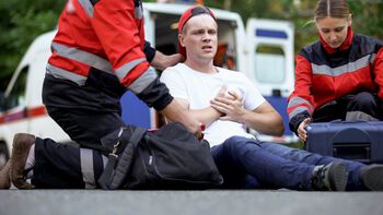 Man med brystsmerter som tas hånd om av ambulansepersonell