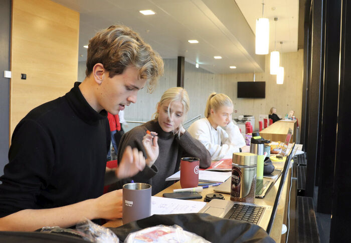 Studenter som sitter sammen på rekke og studerer.