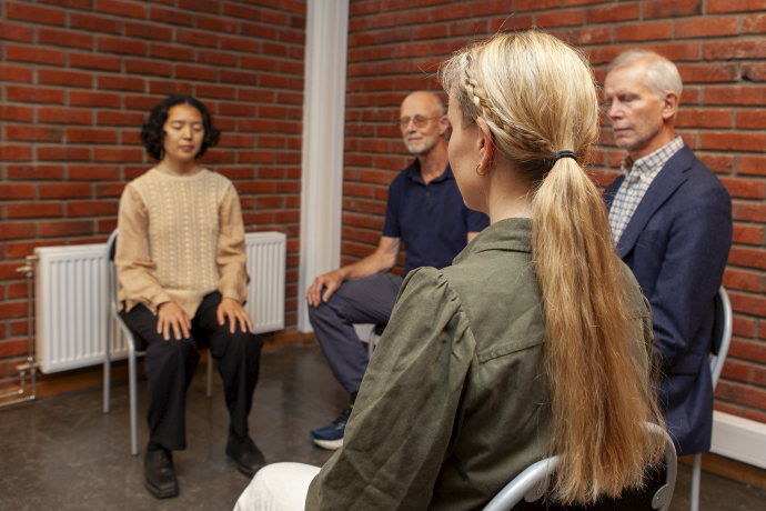 Personer sitter i en halvsirkel og mediterer